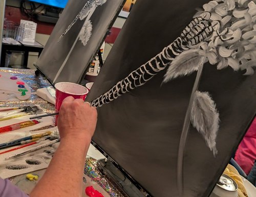 Hand painting a white flower on black canvas