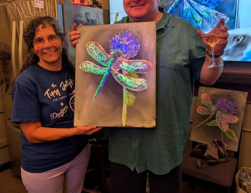 Two friends holding dragonfly paintings