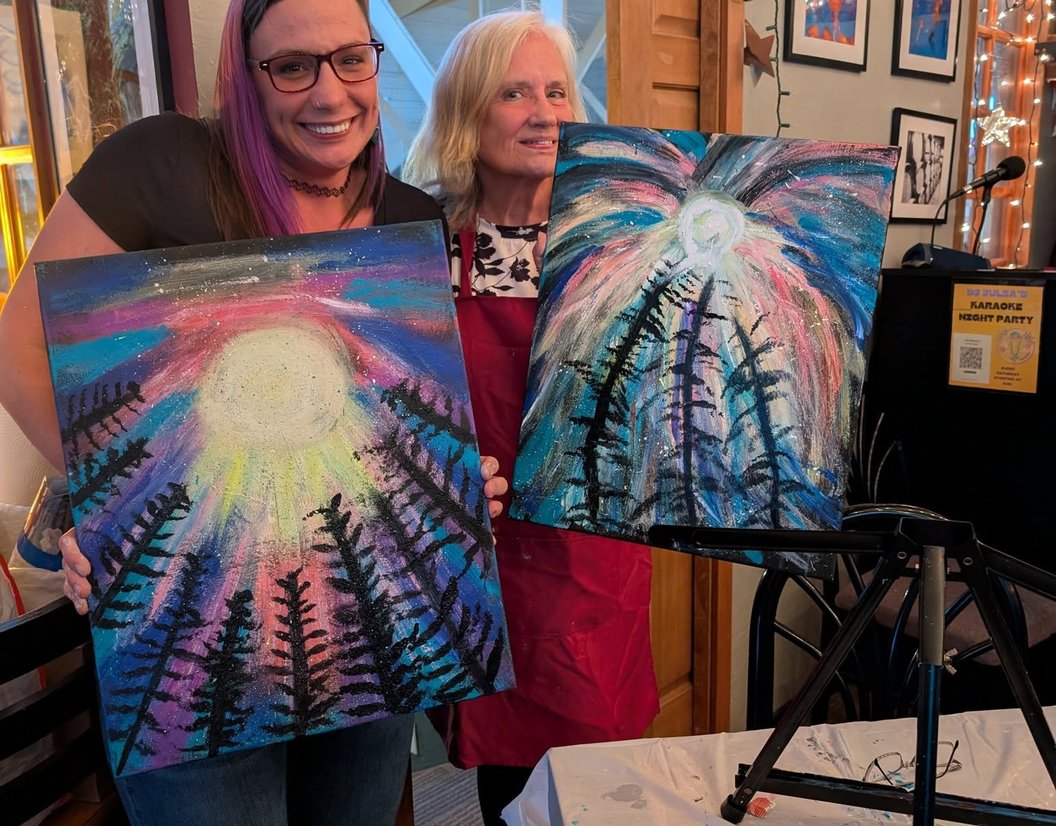 Group holding sunburst paintings at a paint class